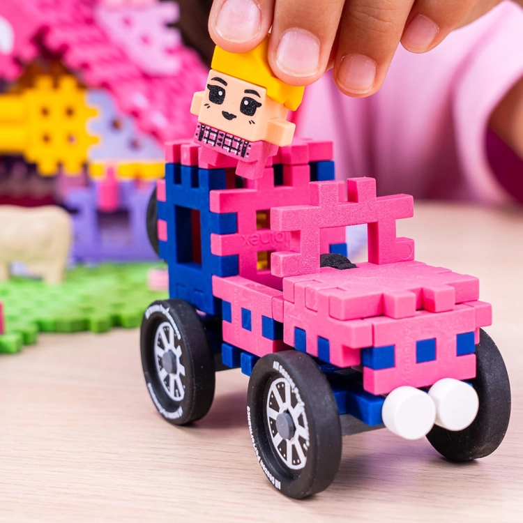 Zbliżenie na budowę różowego samochodu z klocków Marioinex, montowanie figurki kierowcy.