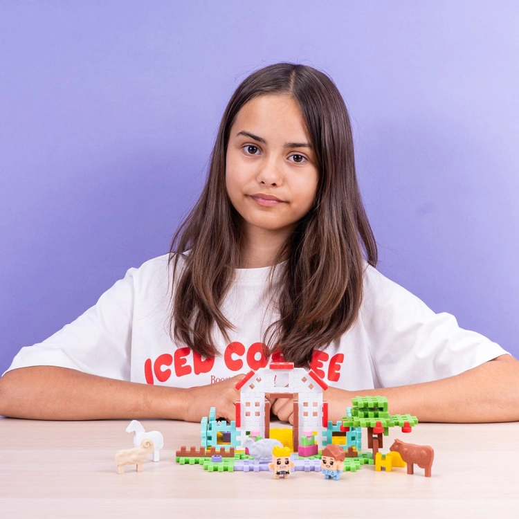 Dziewczynka bawi się klockami Marioinex Mini Waffle Domek Pani Weterynarz na fioletowym tle.