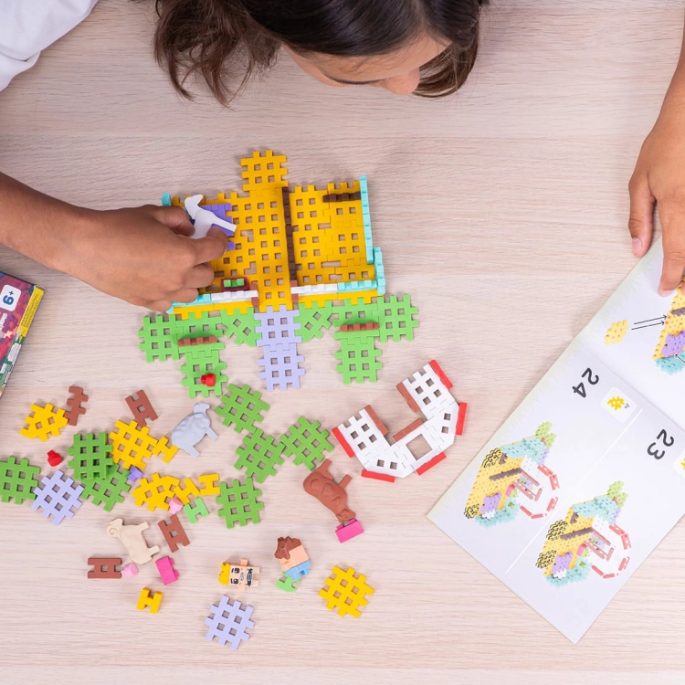 Dziecko układa z klocków Mini Waffle Domek Pani Weterynarz, widoczna instrukcja.