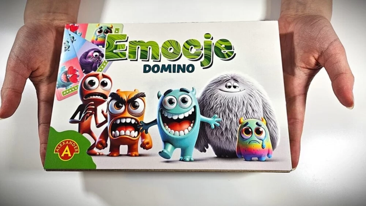 Dłonie trzymają opakowanie gry edukacyjnej Domino Emocje Alexander.