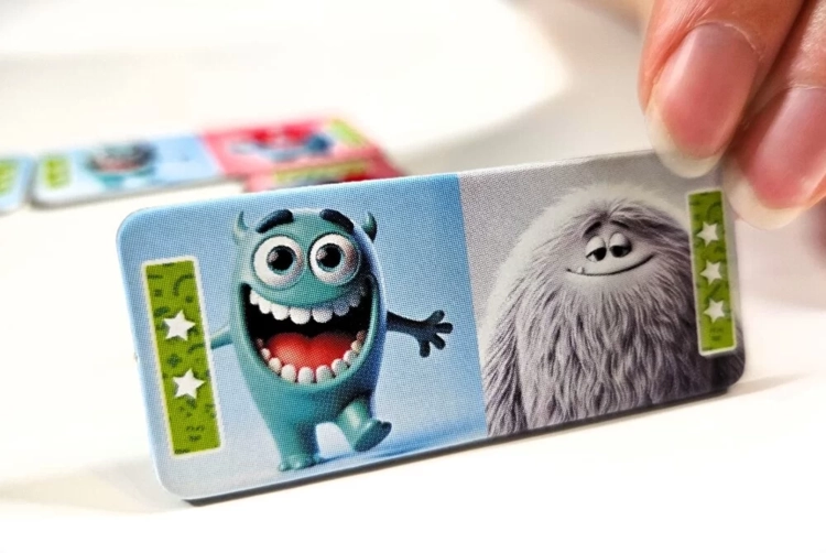 Zbliżenie na element gry Domino Emocje, widoczny potwór radosny i włochaty potwór.