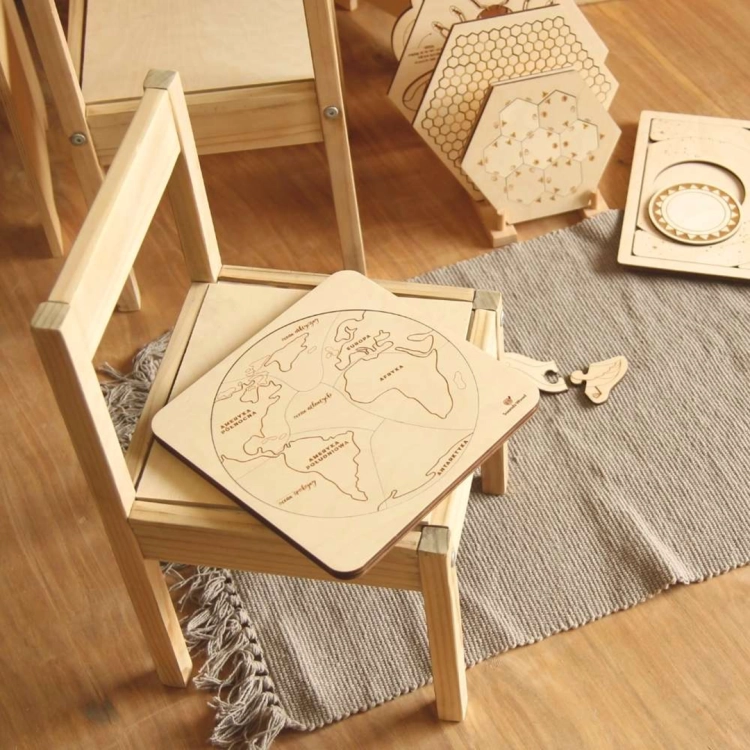 Drewniane puzzle edukacyjne Sounds Wood "Ziemia jest okrągła" na małym drewnianym krześle.