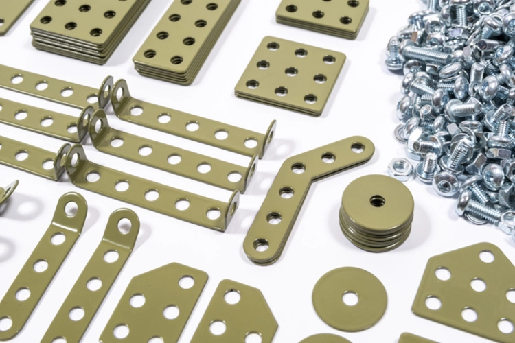 Metalowe elementy zestawu konstrukcyjnego Metalcraft, zielone płytki z otworami i stos śrub.