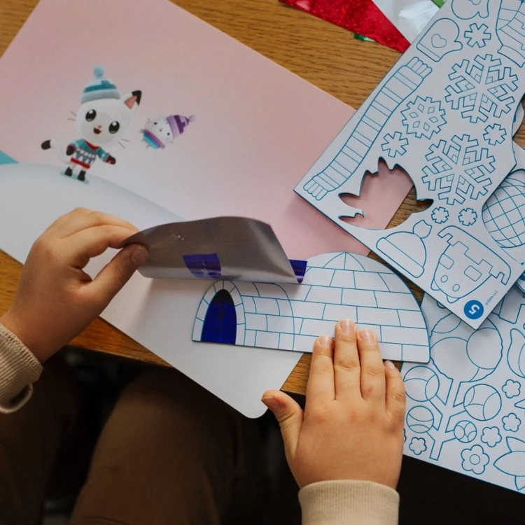 Dziecko nakłada folię na szablon igloo z zestawu Foil Fun Gabby's Dollhouse.