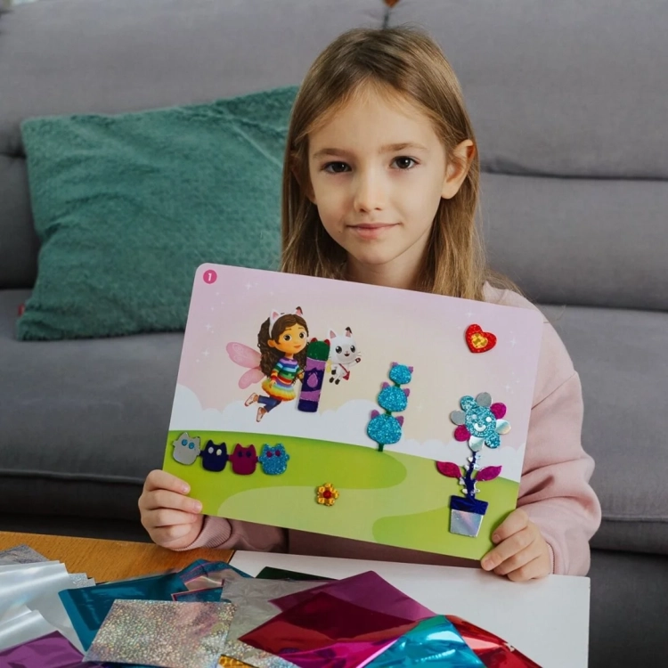 Dziewczynka prezentuje ozdobioną foliową naklejkę z zestawu Foil Fun Gabby's Dollhouse.