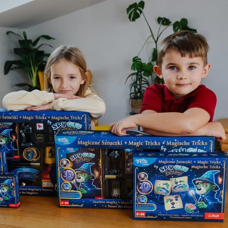 Dzieci uśmiechają się, opierając się na pudełkach zestawów Magiczne Sztuczki by Spy Guy Fantasy Trefl.
