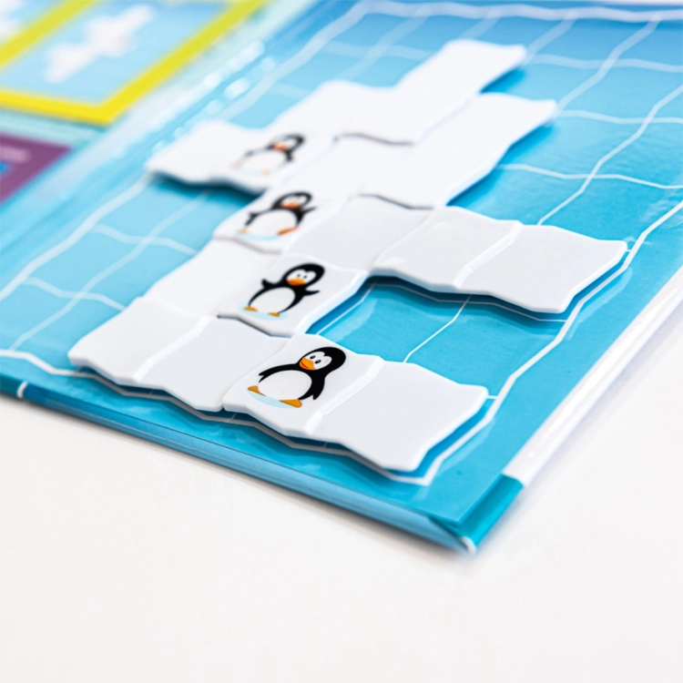 Elementy magnetyczne z pingwinami w rzędzie ułożone na niebieskiej planszy Parada Pingwinów (Widok boczny).