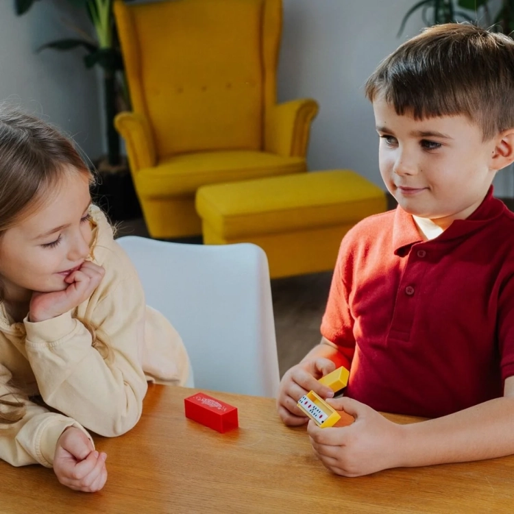 Dzieci bawią się zestawem Magiczne Sztuczki by Spy Guy Fantasy przy stole, chłopiec wykonuje sztuczkę z czarodziejską różdżką.