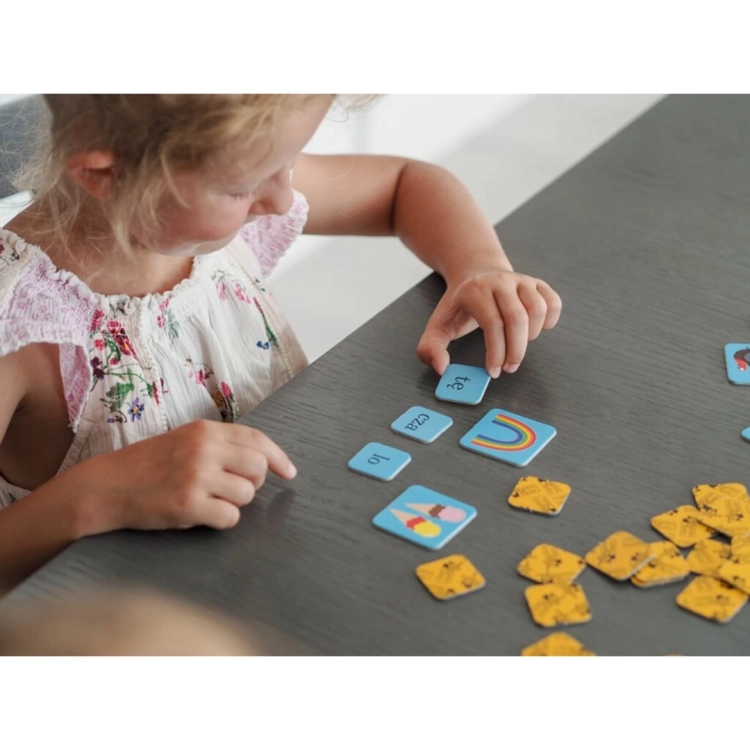 Dziecko układa wyrazy z sylab, korzystając z kolorowych żetonów gry Kapitan Nauka.