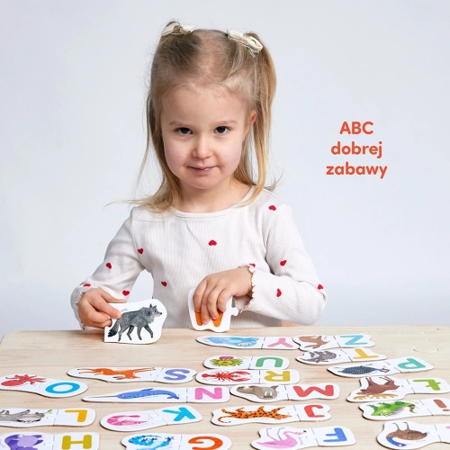 Dziewczynka dopasowująca puzzle CzuCzu Literki przedstawiające zwierzęta i odpowiadające im litery alfabetu.
