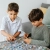 Dwoje dzieci wspólnie układających puzzle Trefl.