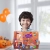 Uśmiechnięty chłopiec trzyma gotową, własnoręcznie ozdobioną planszę przedstawiającą wnętrze domu z kominkiem i postaciami w klimacie Halloween.