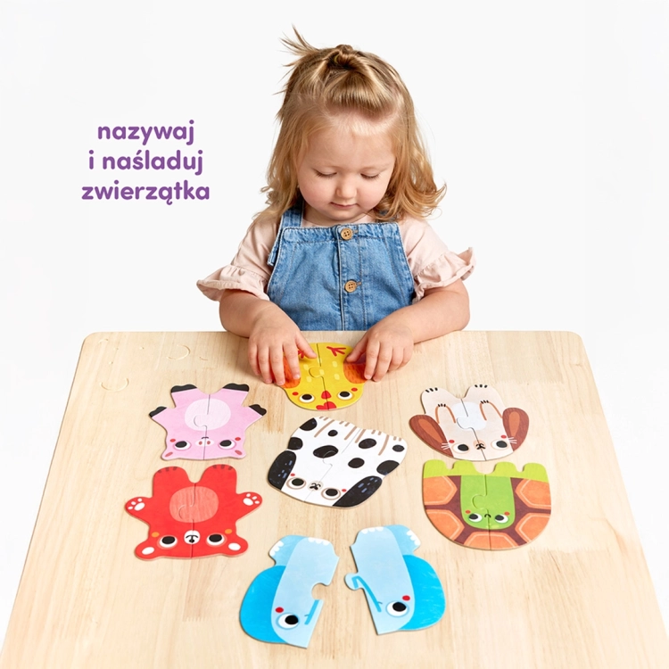 Dziewczynka siedzi przy stole i z zaangażowaniem układa dwuelementowe puzzle przedstawiające kolorowe zwierzątka.