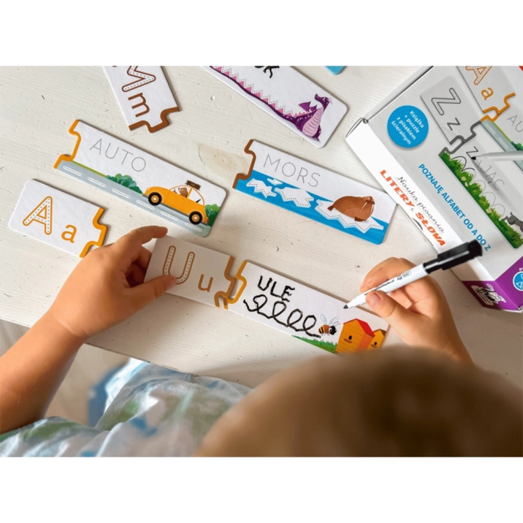 Dziecko używa mazaka do ćwiczenia pisania słów na ścieralnych puzzlach edukacyjnych przedstawiających ule i pszczołę.