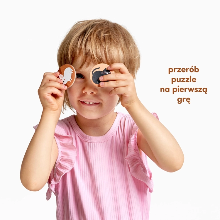 Zbliżenie na dłonie dziecka dopasowujące okrągły żeton do jednej z sześciu kolorowych plansz przedstawiających zwierzęta na farmie.