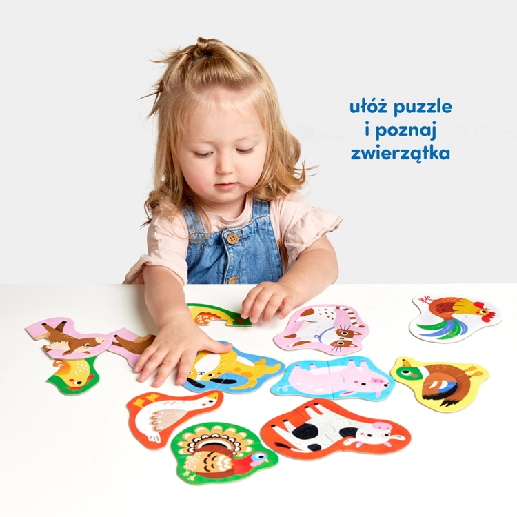 Mała dziewczynka siedzi przy stole i dopasowuje do siebie kolorowe, dwuelementowe puzzle przedstawiające wiejskie zwierzęta.