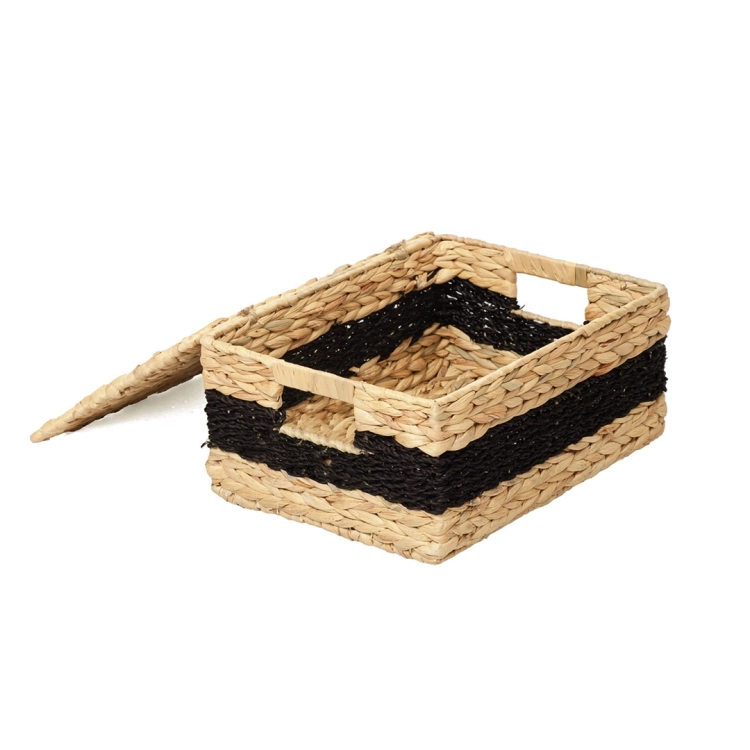 Pleciony kosz z hiacyntu wodnego w naturalnym kolorze z czarnym paskiem, zaprezentowany z podniesioną i opartą obok pokrywą, odsłaniając puste wnętrze i wbudowane uchwyty. Tło białe.