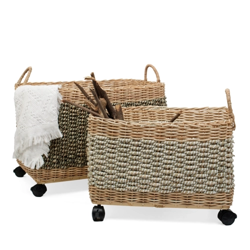 Dwa plecione kosze na zabawki z rattanu i trawy morskiej na kółkach, jeden z białym kocem, drugi z drewnem.