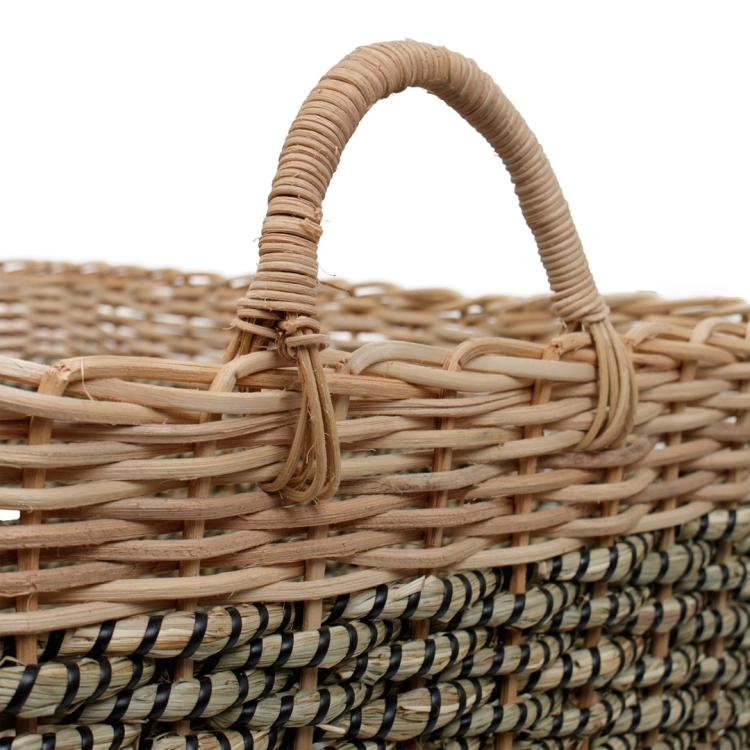 Zbliżenie na pleciony uchwyt i staranny splot rattanowego kosza w kolorach naturalnym i czarno-zielonym.