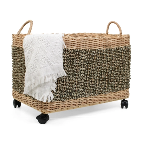 Mobilny kosz rattanowy na kółkach z dekoracyjnym białym kocem, dwukolorowy splot, widoczne rączki.