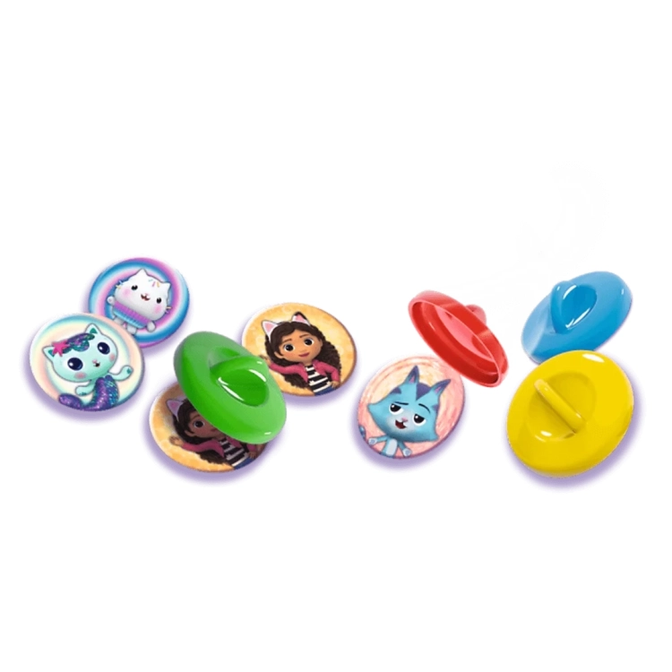 Rozłożone elementy gry: okrągłe żetony z postaciami z bajki Koci Domek Gabi oraz kolorowe plastikowe przykrywki do zakrywania par.