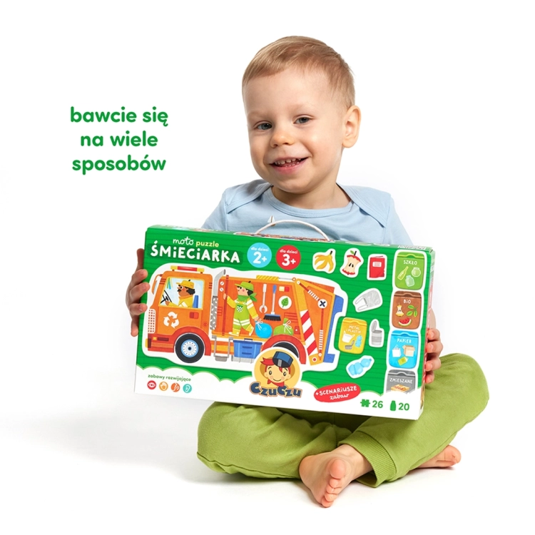 Uśmiechnięty chłopiec trzyma duże, zielone pudełko "Moto puzzle Śmieciarka" marki CzuCzu, przeznaczone dla dzieci powyżej 2 roku życia.