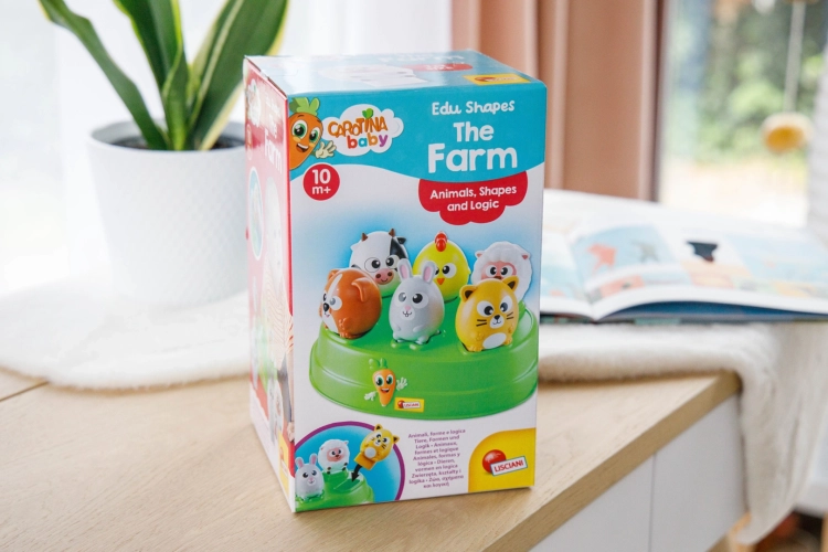 Opakowanie sortera Carotina Baby Farma ustawione na jasnym blacie obok rośliny doniczkowej w domowym wnętrzu.