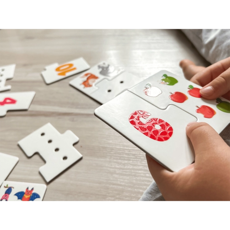 Detal dłoni trzymającej ułożone puzzle z cyfrą 6; widoczna wypukła, prążkowana struktura powierzchni cyfry.