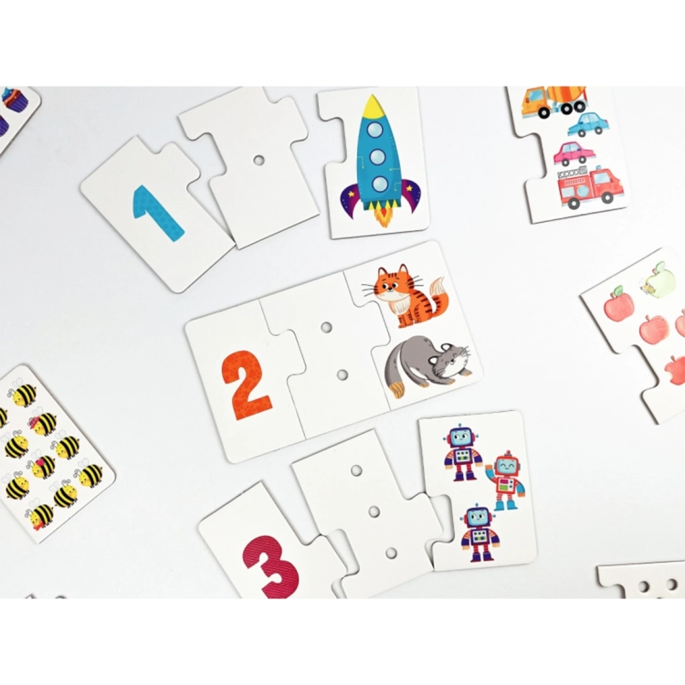 Rozłożone na białym tle elementy puzzli sensorycznych z cyframi 1, 2, 3 oraz rakietą, kotkami i robotami.