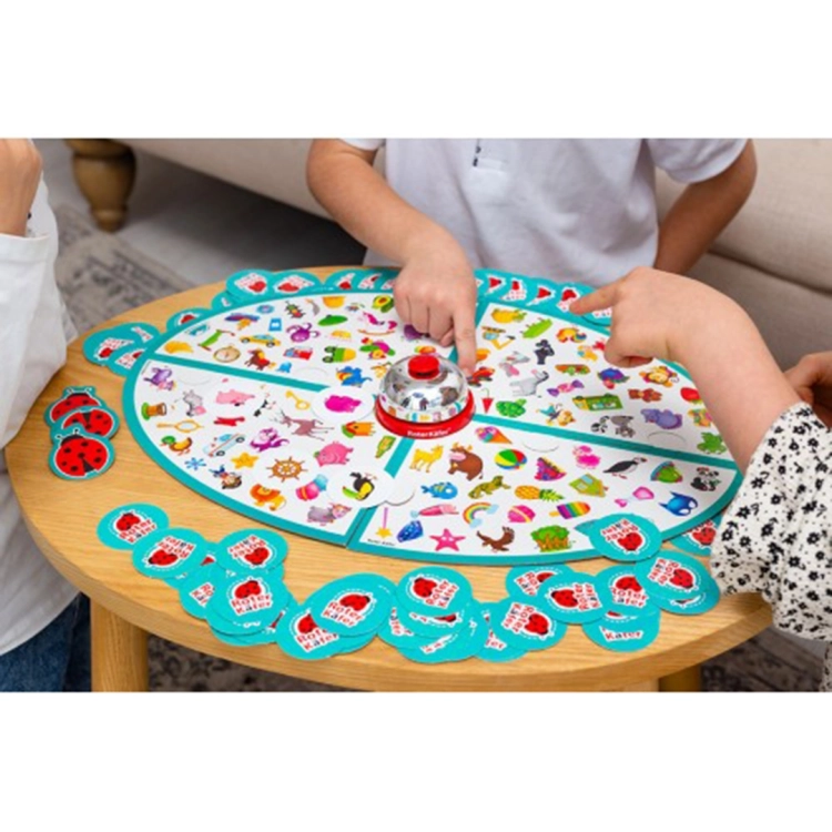 Zbliżenie na dłonie dzieci wskazujące kolorowe obrazki zwierząt i przedmiotów na białej planszy podzielonej na cztery części.