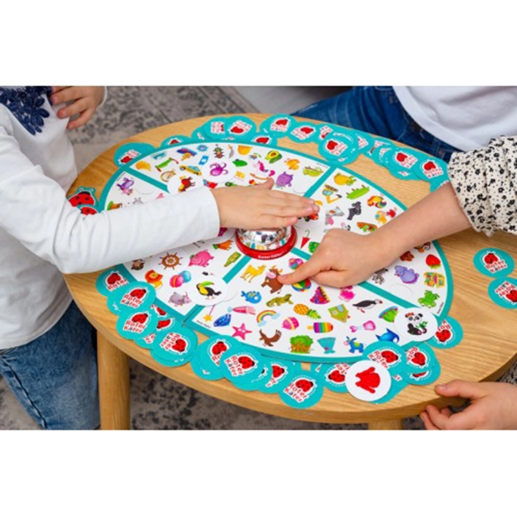 Dziecko uderza dłonią w dzwonek na środku planszy podczas emocjonującej rozgrywki w grę rodzinną; widoczne liczne żetony z biedronką.