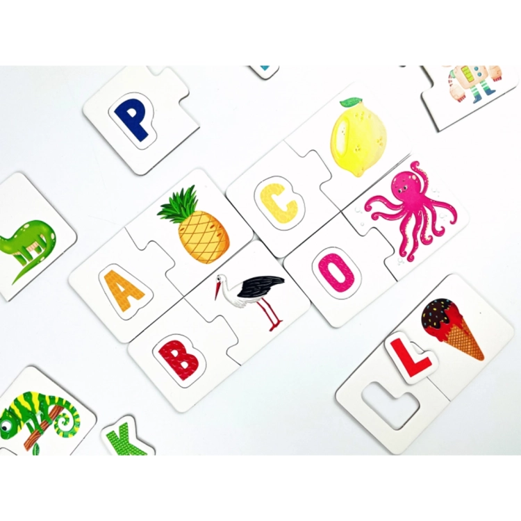 Detal kilku zestawów puzzli sensorycznych (ananas, bocian, cytryna, ośmiornica, lody) rozrzuconych swobodnie na jasnym tle.