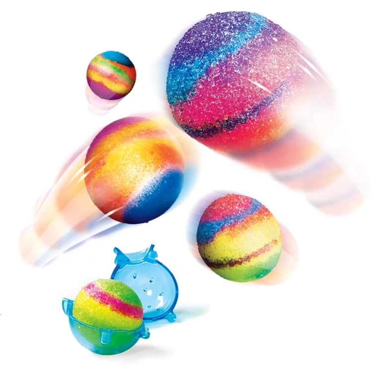 Kilka wielokolorowych, brokatowych piłeczek w ruchu na białym tle oraz niebieska forma do ich tworzenia.