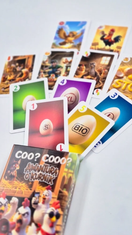 Perspektywiczne ujęcie kart wysuwających się z opakowania gry. Na pierwszym planie kolorowe karty z jajkami S oraz BIO.