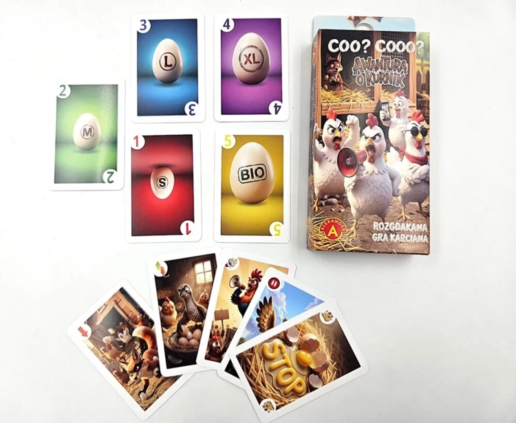 Zestaw kart do gry rozłożony na białym tle obok pudełka. Widoczne karty z jajkami o różnych rozmiarach (S, M, L, XL, BIO) oraz karty akcji z grafikami kur i lisów.