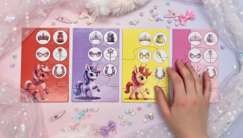 Cztery kolorowe planszetki z jednorożcami i akcesoriami do zbierania. Obok widoczna ręka dziecka oraz ozdobne koraliki i spinki.