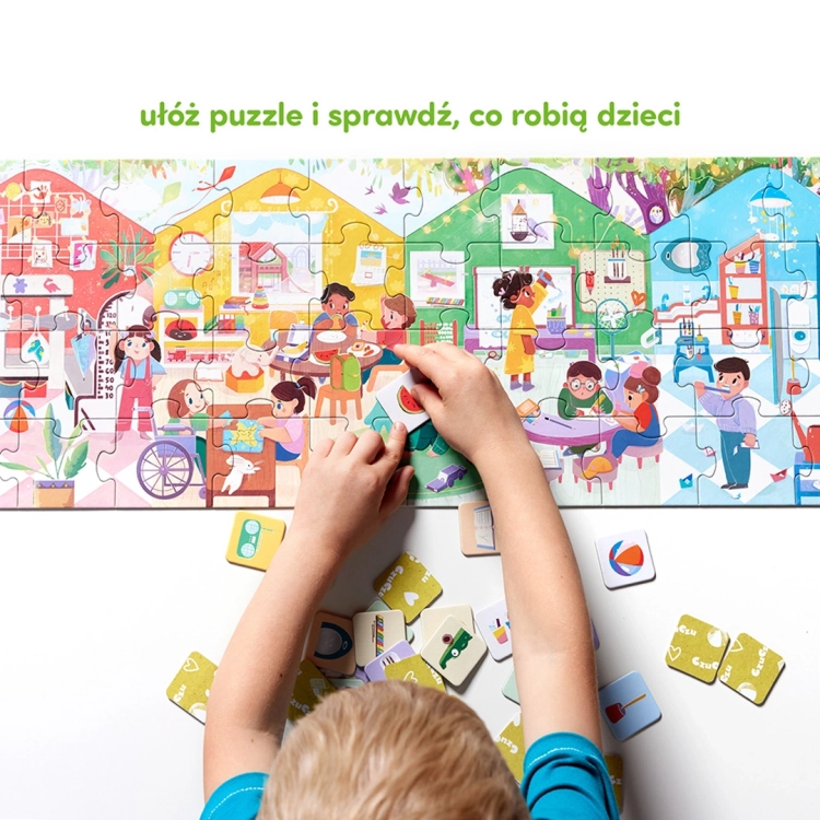 Dziecko układa kolorowe puzzle przedstawiające sceny z życia przedszkola. Na pierwszym planie rączki dopasowujące żeton z arbuzem do ilustracji.