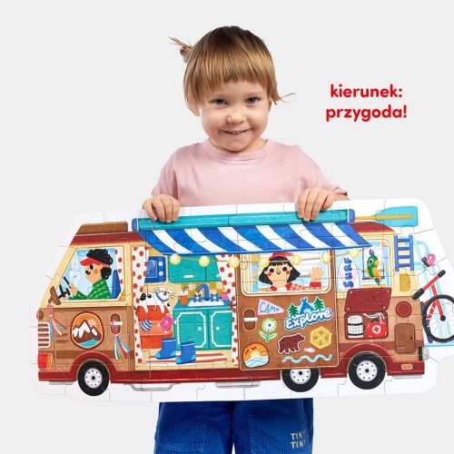 Dziecko trzyma ułożone, duże puzzle CzuCzu w kształcie brązowego kampera. Napis: „kierunek: przygoda!”.