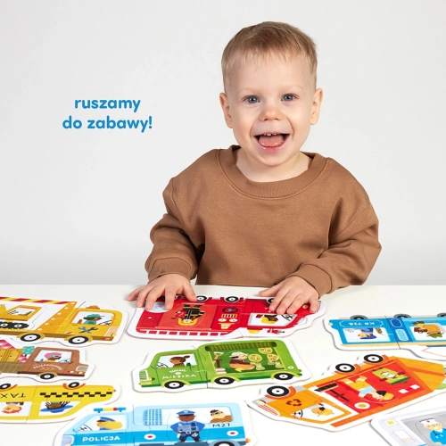 Uśmiechnięte dziecko siedzi przy stole, na którym leżą kolorowe puzzle CzuCzu przedstawiające różne pojazdy miejskie. Napis: ruszamy do zabawy!