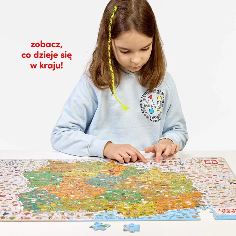 Dziewczynka w błękitnej bluzie pochylona nad niemal ułożonymi puzzlami Mapa Polski, wskazująca palcem na detale ilustracji.