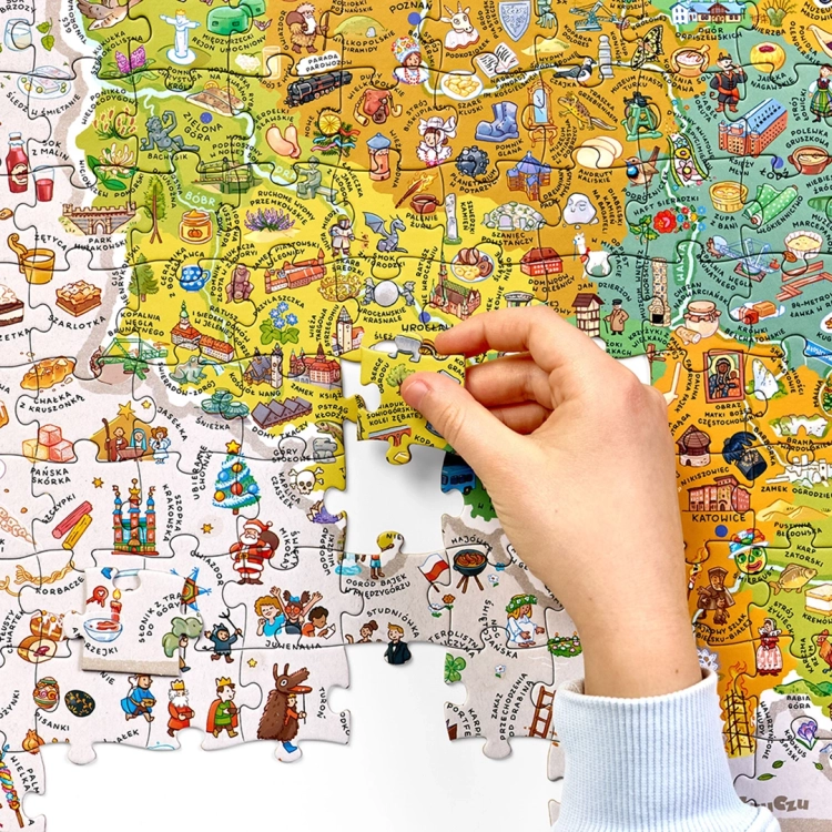 Zbliżenie na dłoń dziecka dopasowującą brakujący element do kolorowej układanki z mapą Polski i regionalnymi symbolami.