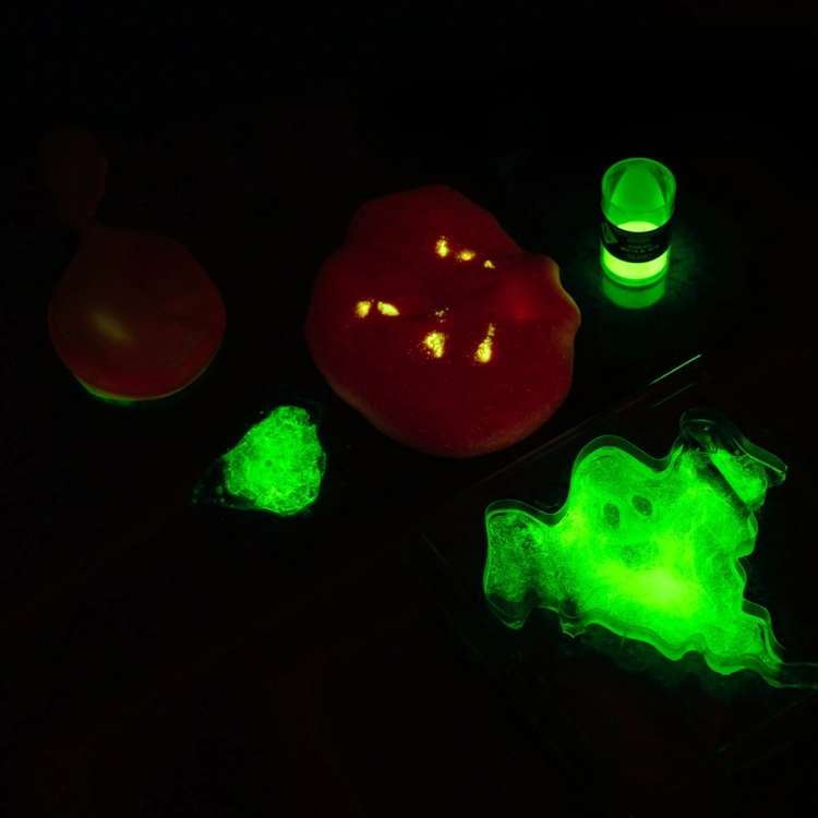 Efekt fluorescencyjny: świecący w ciemności zielony slime w kształcie ducha, masa w balonie i słoiczek z pigmentem.