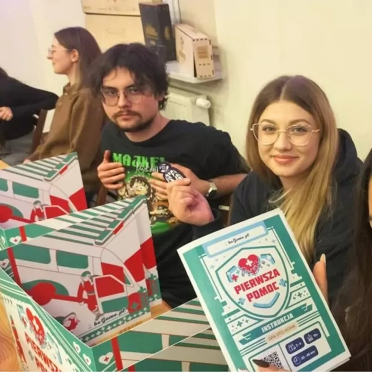 Młodzi ludzie grający w grę planszową Pierwsza Pomoc BeGame – nauka ratownictwa przez zabawę.