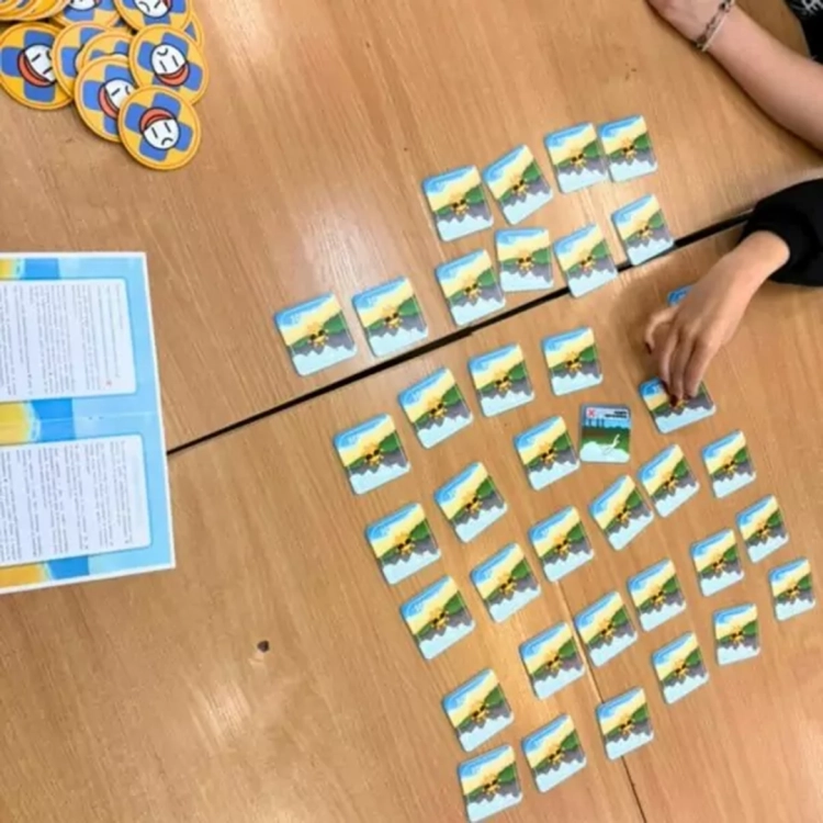 Rozgrywka w grę edukacyjną Bezpieczne wakacje, widoczne kafelki memo i instrukcja na stole.