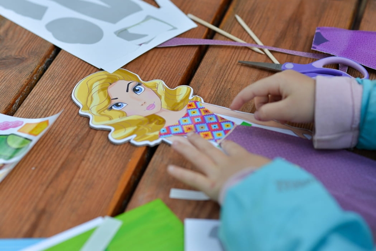 Ręce dziecka wycinające ubranka – rozwój zdolności manualnych.