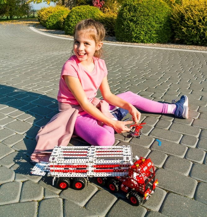 Elementy zestawu konstrukcyjnego – metalowe blaszki, śrubki, koła i narzędzia.